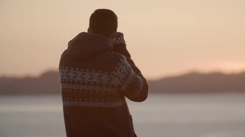 A man is taking photographs of a sunset