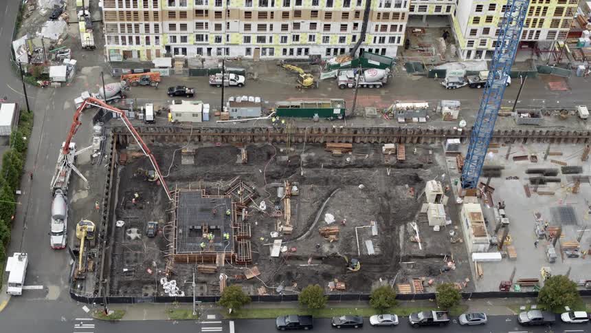 Construction workers pour concrete to form the foundation of a new apartment building