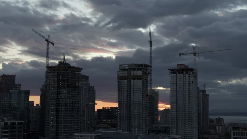 Ascending orbit around three new high-rise buildings under construction as cranes tower above them