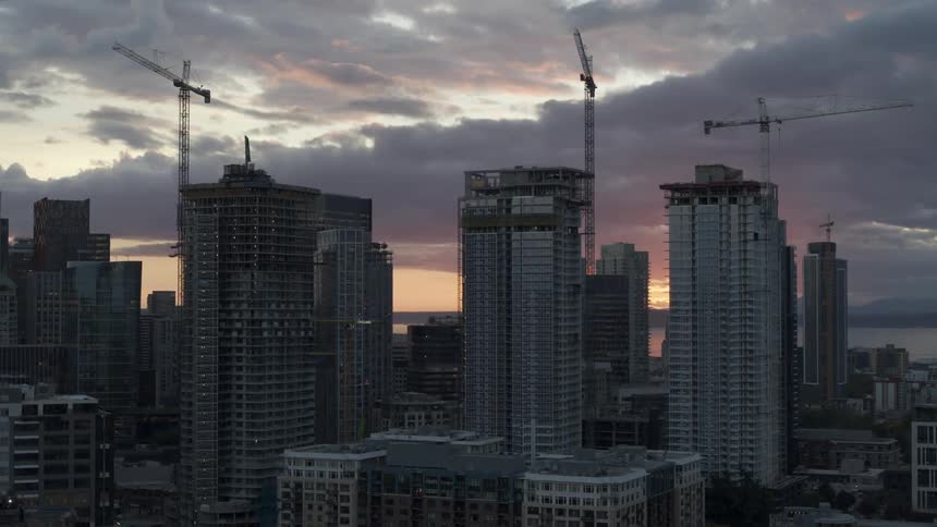 Orbit around three new condo buildings under construction in downtown Seattle at sunset