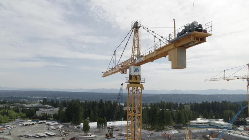 Close approach alongside a tall tower crane working over a major construction site