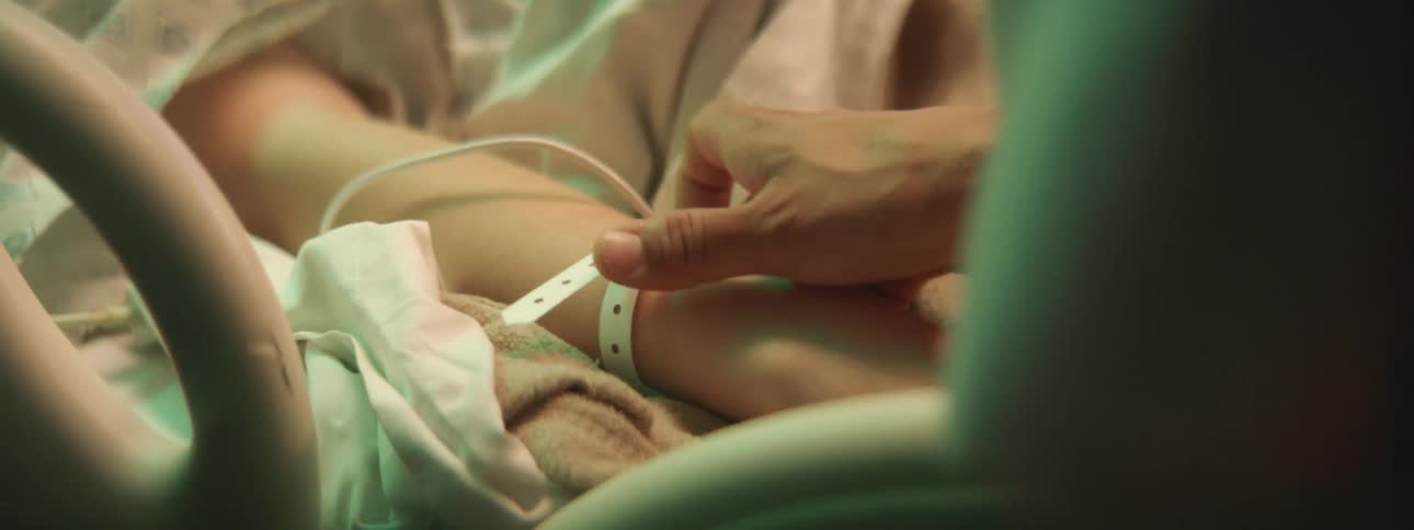 A man comforts a person lying in a hospital bed