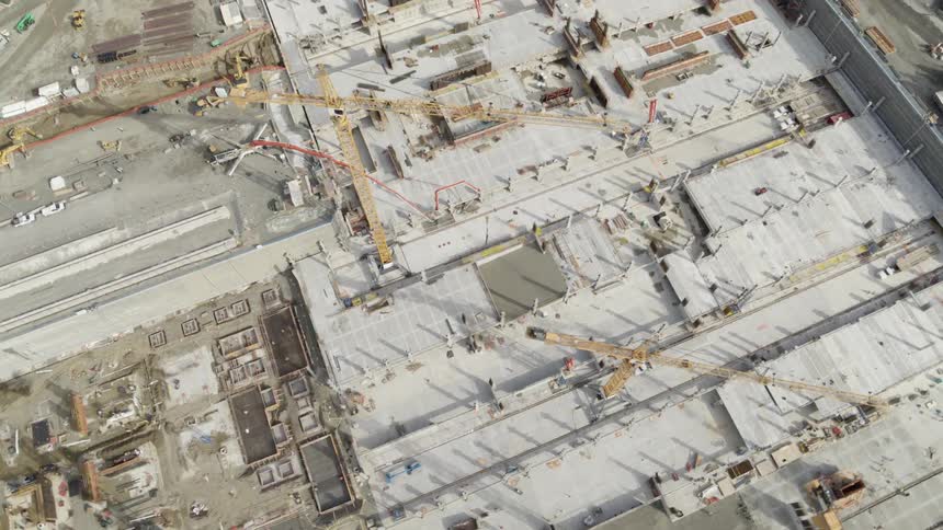 Top down view of multiple tower cranes working above a new building foundation