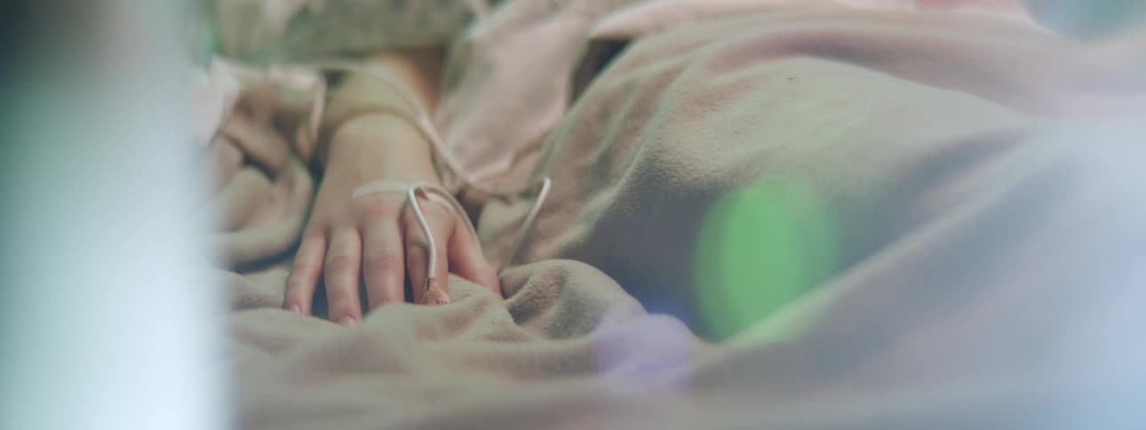 Intravenous therapy on the arm of a patient laying in a hospital bed