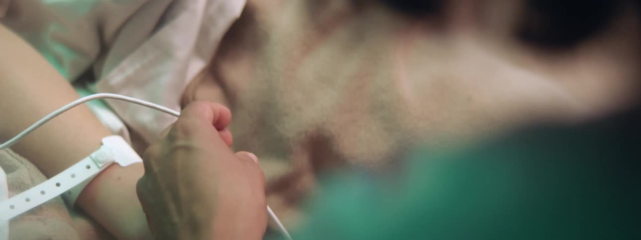 Nurse adjusts cord standing near patient lying on hospital bed