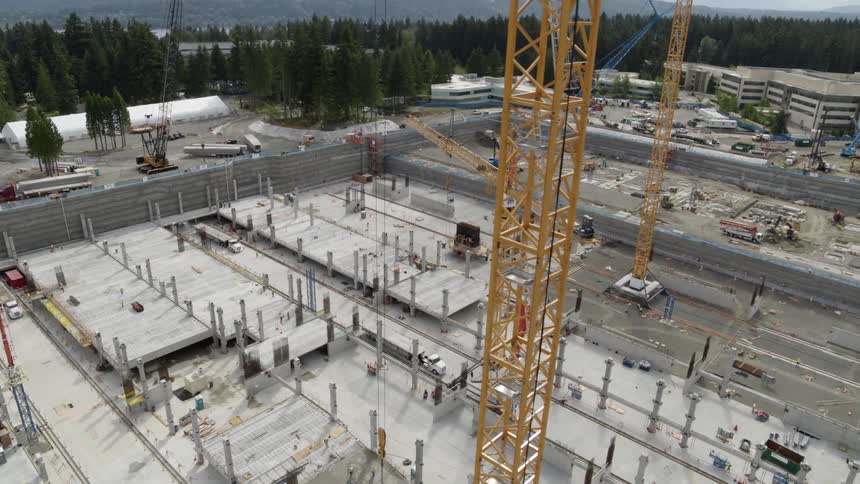 Multiple yellow tower cranes working in tandem over a large construction site