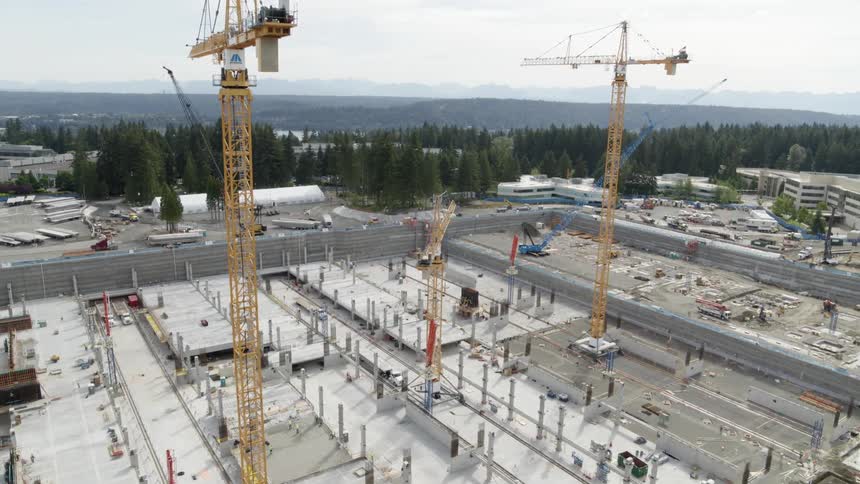 Slow traverse along a large construction pit as tall cranes loom overhead