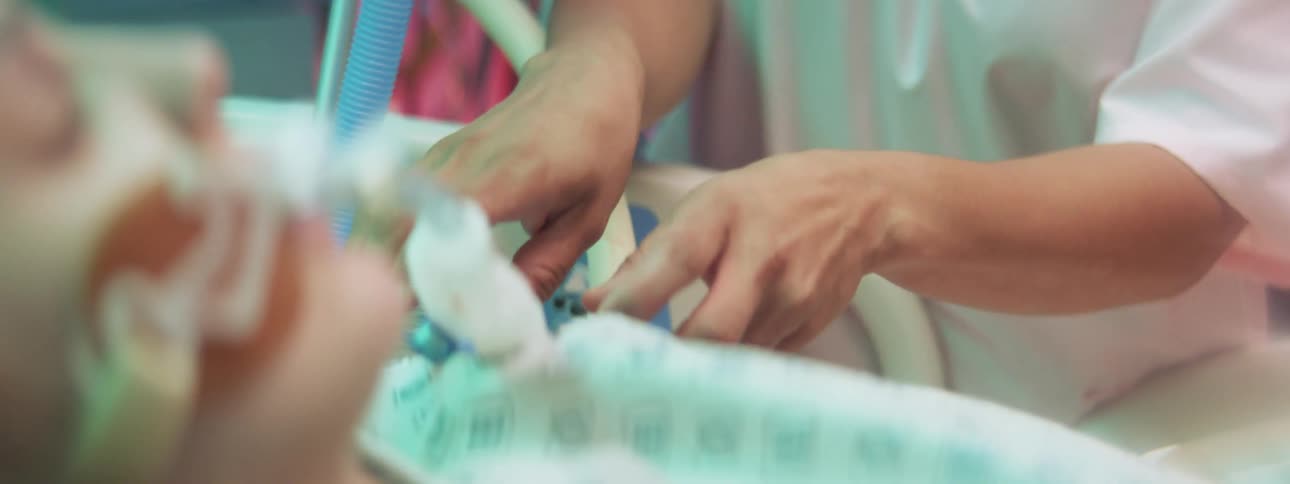 Hospital nurse adjusts tube and breathing apparatus of unconscious patient