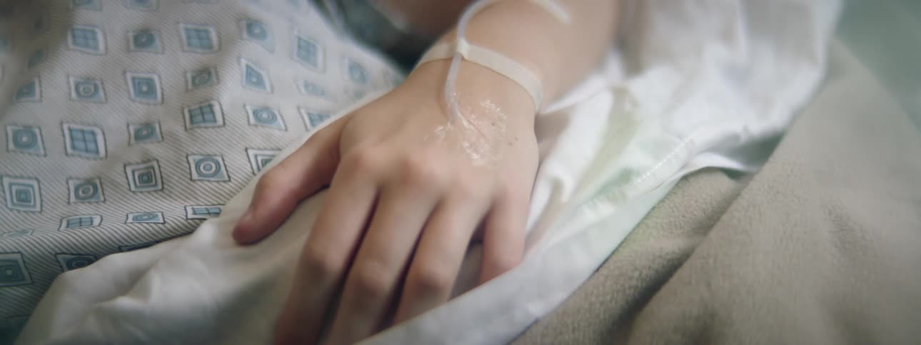 A patient laying in a hospital bed with an iv in their arm