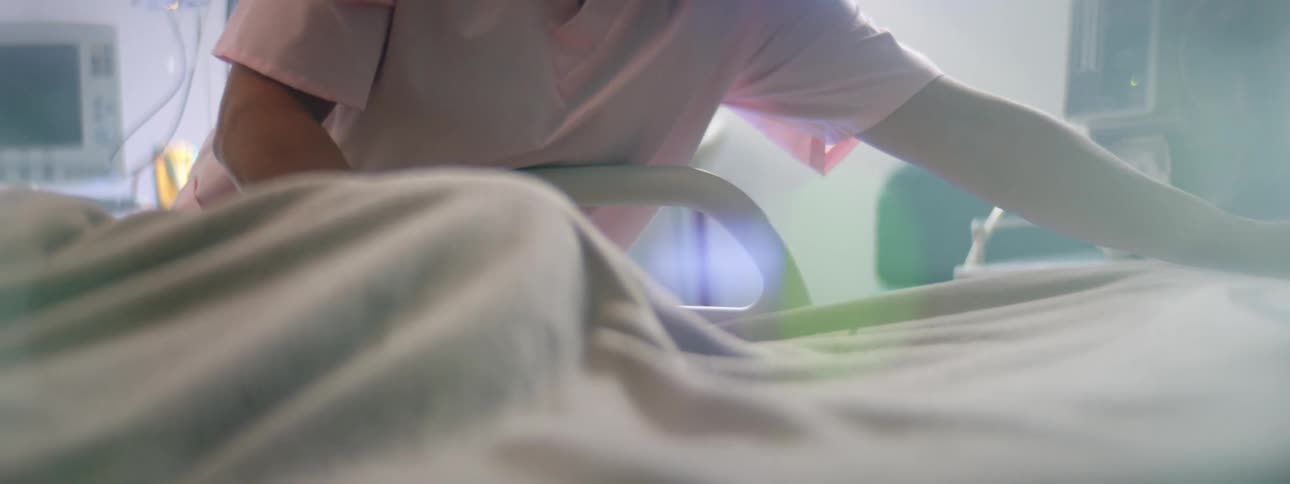 A nurse smooths the sheets on a patients hospital bed
