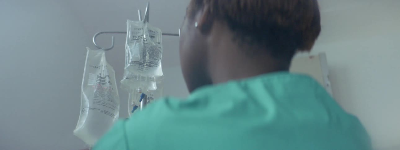 A nurse in a hospital hangs bags of fluid on an iv pole