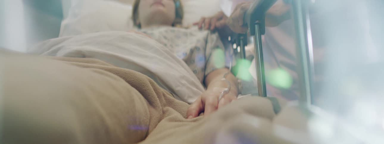 A female patient in a hospital bed is being transported by medical staff