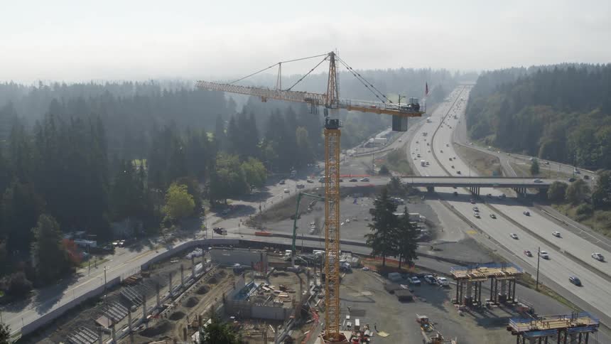 Tilt down reveal of a construction site next to a freeway and suburban neighborhood