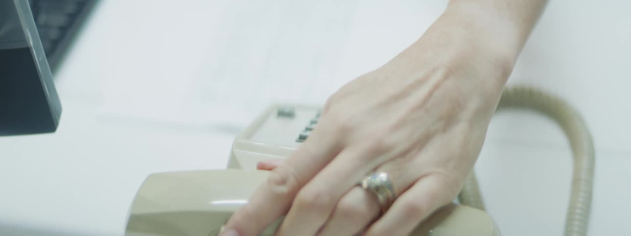 A nurse works on her computer while on the phone and hangs up