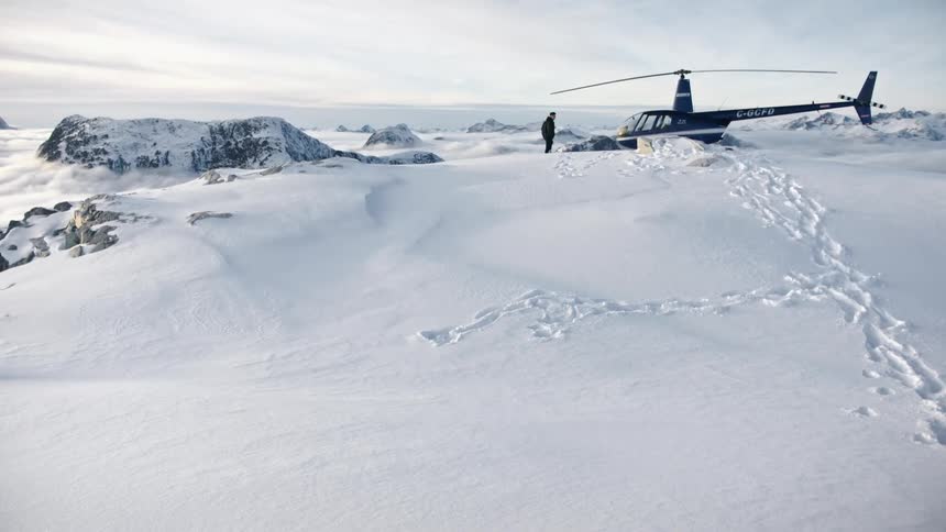 A man standing in front of a helicopter on snow covered land