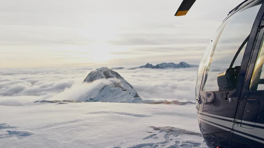 A helicopter on top of snow covered mountain