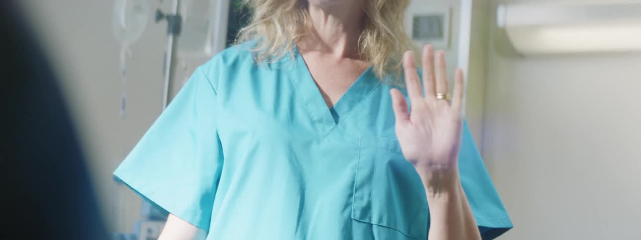 A doctor is waving to someone in the hospital room