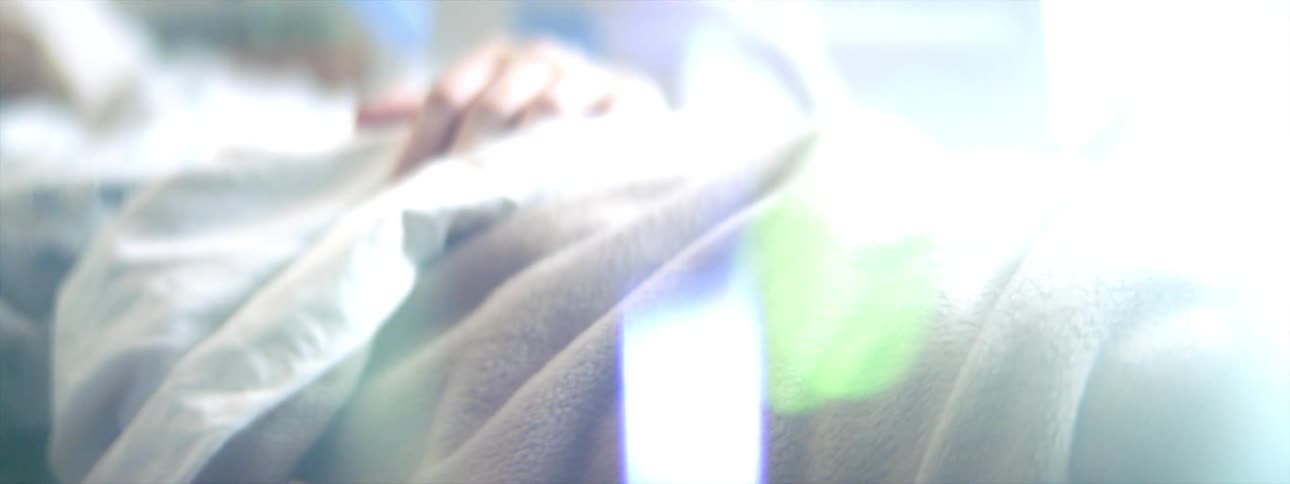 A woman lies in a hospital bed hooked up to medical equipment