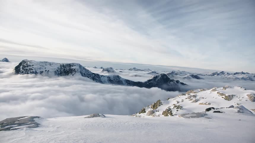 Towering snow covered mountains are so tall that their peaks stand above the clouds