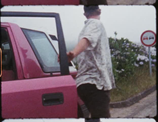 A man exits the driver side of his vehicle to open up the rear door of it