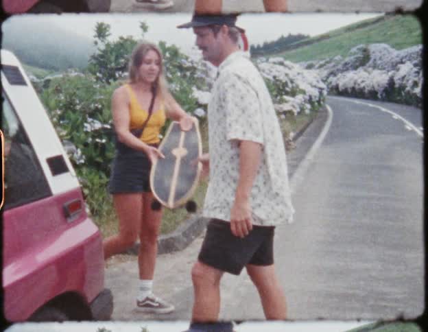 Two friends take skateboards from the trunk of a car in a road in the mountains