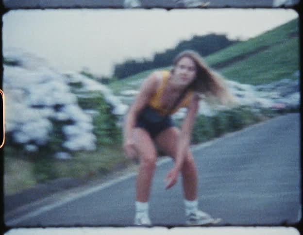 A film strip of a teenage girl and her father skateboarding down a road lined with flowers
