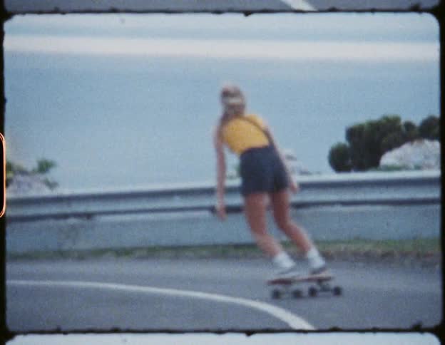 A blonde haired female skateboarding down a road outdoors