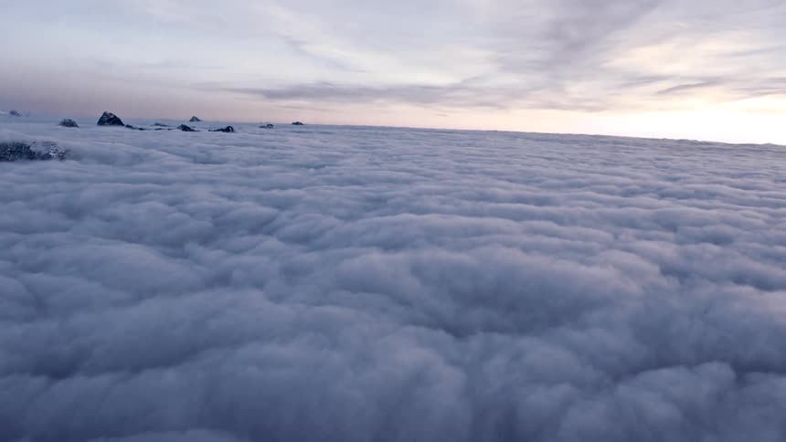 The peaks of mountains poke through a sea of clouds during the day