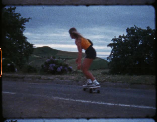 Woman on a skateboard riding down an asphalt street at daytime