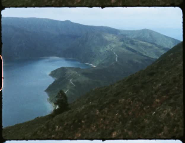 The green slopes of a mountain near a lake on film