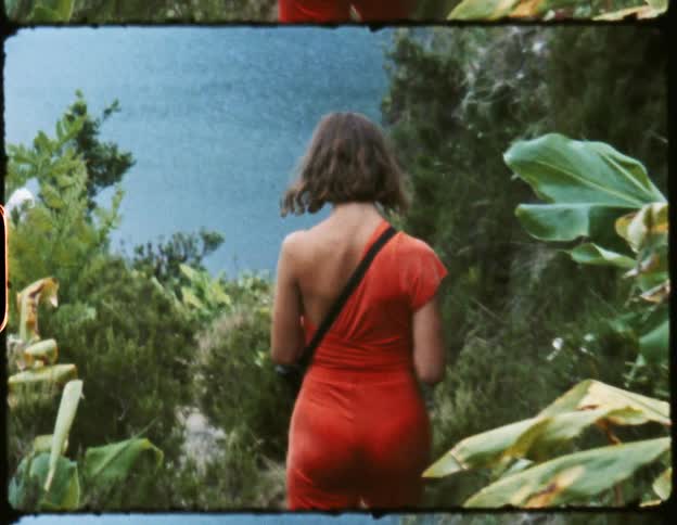 Woman walks down a small hill next to a mountain in front of a lake