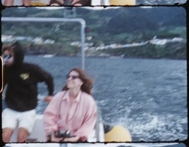 An old film of people on a boat laughing as they drive through a lake