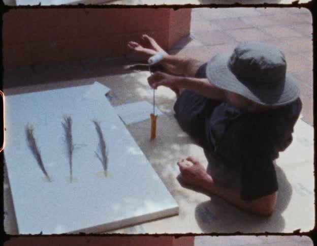 A film strip of a man lying on the ground next to artwork