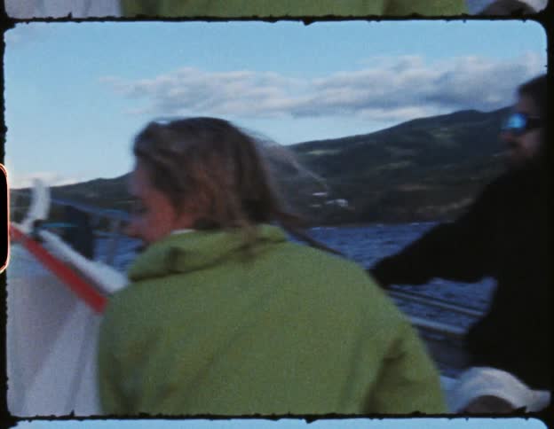 A man and a woman sitting on a boat with the sky and clouds in the background