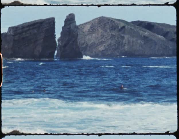 Three surfer paddle away from shore on their surfboards on a sunny day