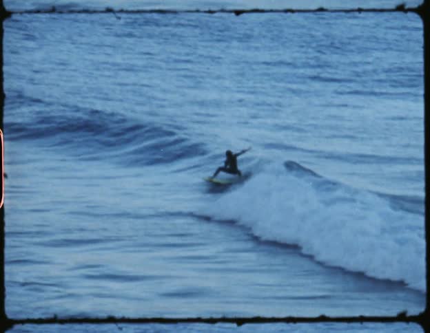 A man surfs on a wave in the ocean with very little sunlight