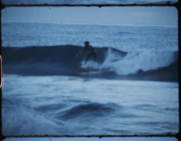 A person on a surfboard surfing on a wave in the ocean with the sky and clouds in the background