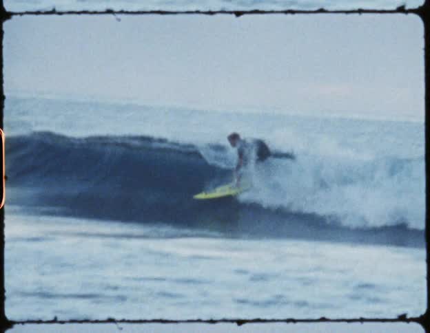 Man riding a yellow surfboard on a small wave falls off into the water