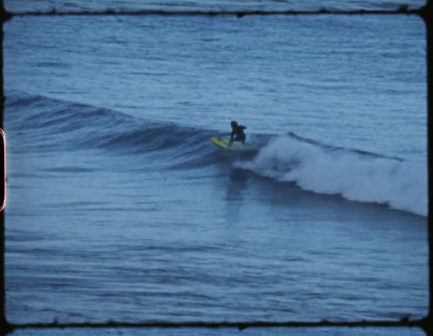 A man rides on a yellow surfboard on a wave in the ocean