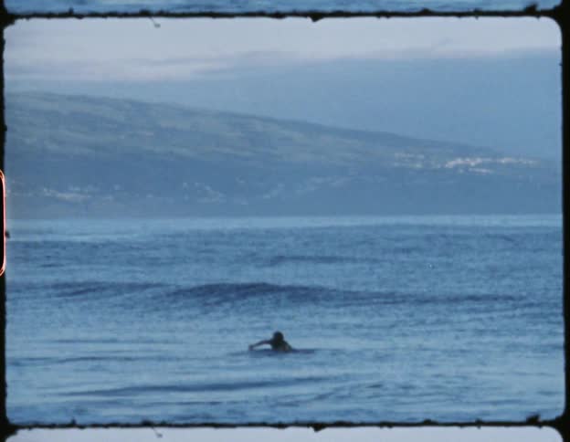 Man swimming in the ocean next to the shore in the evening as the tide rolls in