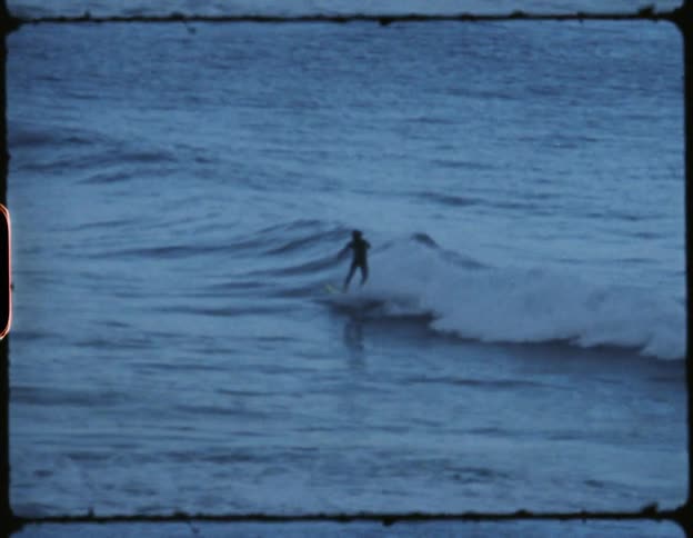 A man rides a yellow surfboard in the ocean far from the coast