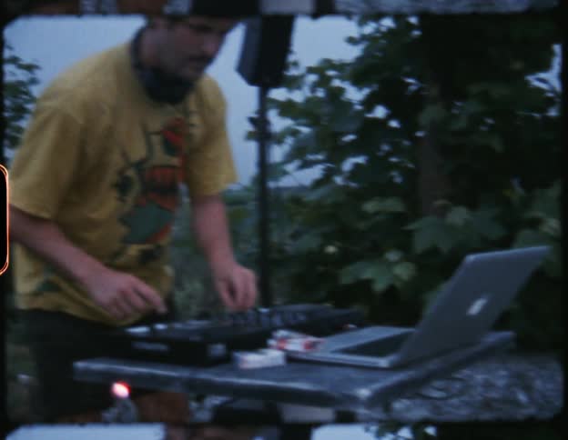 A vintage film of a man setting up audio equipment above the shore