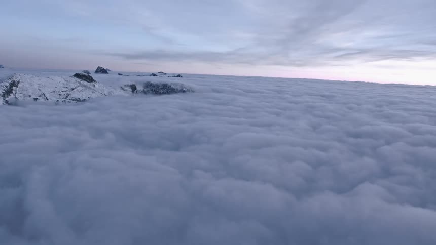 Only the peaks of mountains are visible under a blanket of dense fluffy clouds