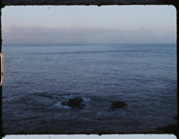 Ocean view with waves splashing up against small rocks in the water