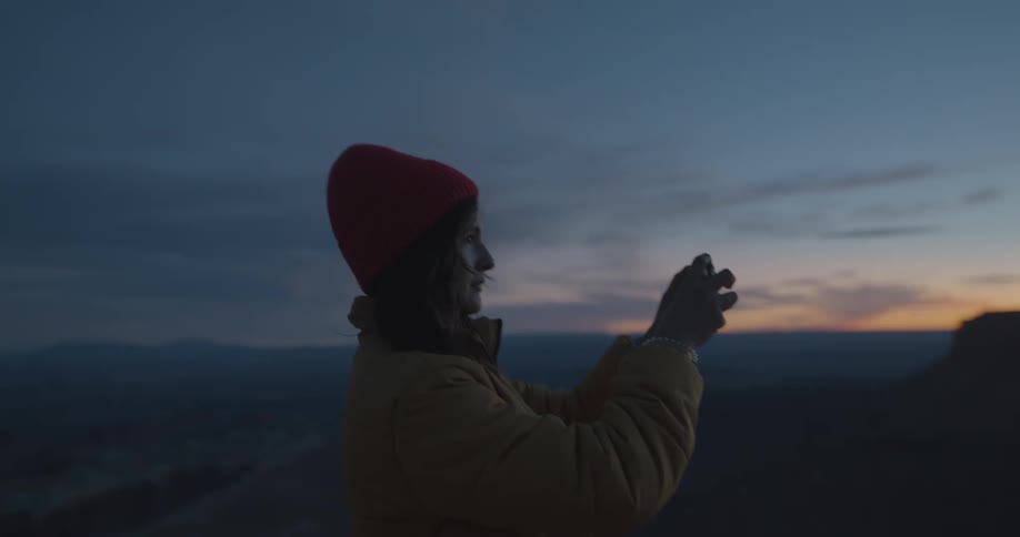 A woman uses her cell phone to take a picture of a beautiful sunset