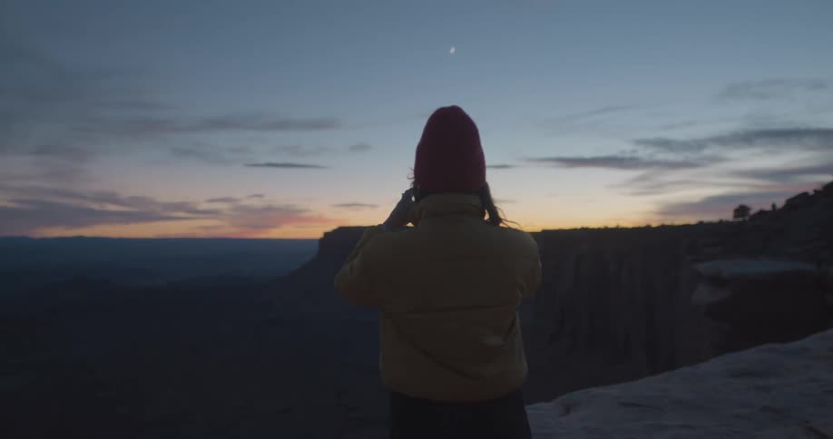 A woman stands on top of a hill watching the sun rise