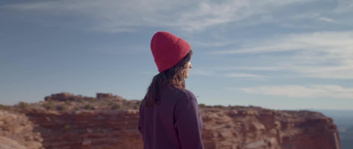 A woman looks out into the distance near a rock face