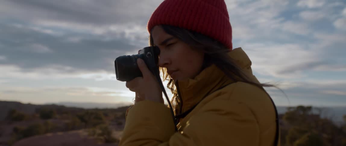A woman stands on the summit of a canyon and takes photos with a dslr