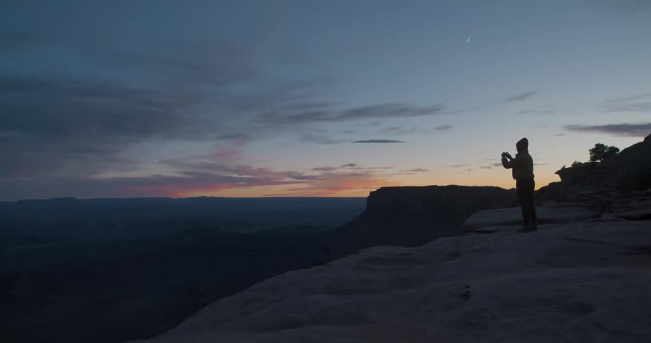 A person takes a photo at dusk
