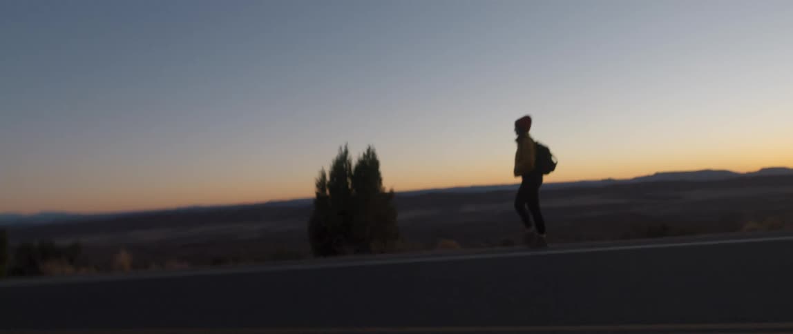 A person his hitchhiking down the road